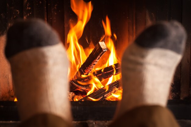 Foto calentamiento de pies cerca de la chimenea.