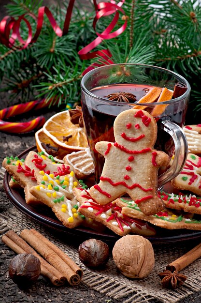 Calentamiento de vino caliente, especias y galletas de jengibre sobre un fondo de madera en estilo rústico