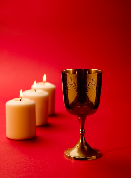 Foto cálice católico apostólico e romano com velas acesas fundo vermelho