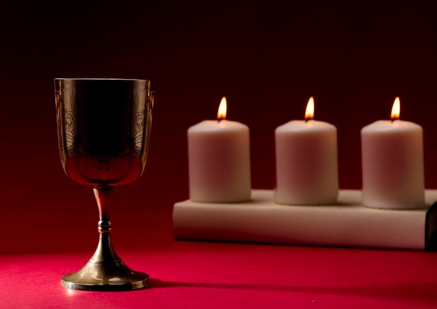 Foto cálice cristão na bíblia estão sobre uma mesa com três velas