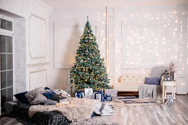 Cálido, acogedor, hermoso y moderno diseño de habitación en suaves colores claros decorados con un árbol de Navidad y elementos decorativos para el nuevo año
