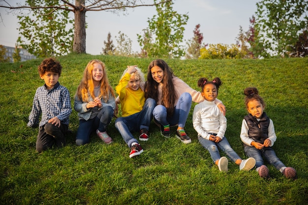 Cálido. Grupo interracial de niños, niñas y niños jugando juntos en el parque en verano. La amistad no tiene raza. Felicidad, infancia, educación, concepto de diversidad. Luce feliz y sincero.