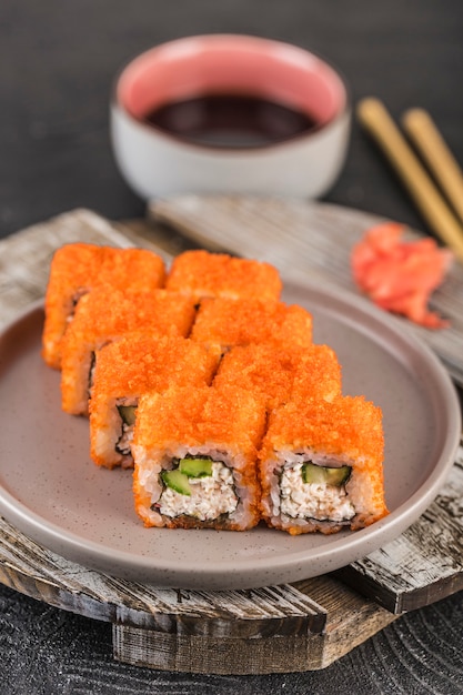 California roll com caviar vermelho e abacate em cream cheese em uma superfície escura