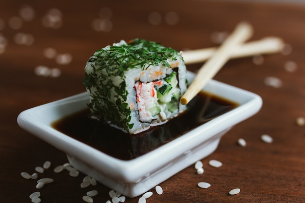 California Roll in Greens in Sojasauce mit Stäbchen