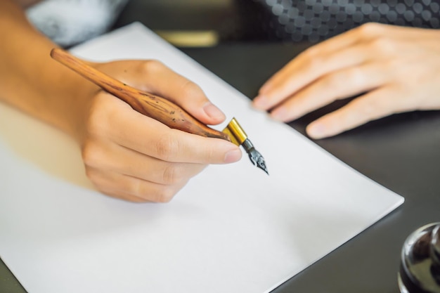 Calígrafo Mujer joven escribe frase en papel blanco Inscribir letras decoradas ornamentales Caligrafía diseño gráfico letras concepto de creación de escritura a mano