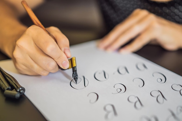 Calígrafo Mujer joven escribe frase en papel blanco Inscribir letras decoradas ornamentales Caligrafía diseño gráfico letras concepto de creación de escritura a mano