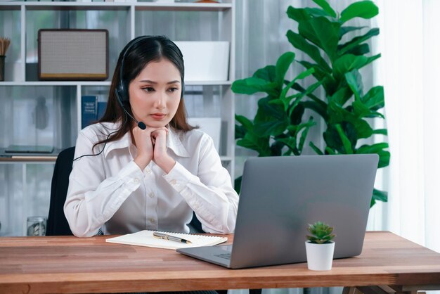 Call center asiático com fone de ouvido e microfone trabalhando em seu laptop Operadora oferece atendimento excepcional ao cliente Agente de call center de suporte ajudando o cliente em consulta Entusiasmado