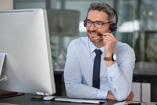 Foto call center de empresário e sorriso com fones de ouvido no computador em telemarketing de atendimento ao cliente ou suporte no escritório consultor de homem ou consultoria de agente para aconselhamento on-line ou televendas no local de trabalho