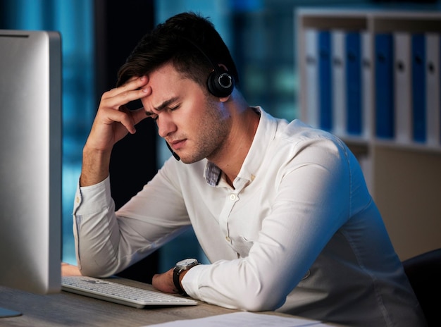 Call center de estresse e atendimento ao cliente com um consultor de homem sofrendo de esgotamento enquanto trabalhava tarde da noite Comércio eletrônico de CRM e conformidade com um funcionário do sexo masculino que trabalha no varejo ou vendas