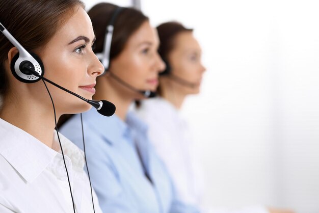 Call Center. Gruppe von Bedienern bei der Arbeit. Konzentrieren Sie sich auf schöne Geschäftsfrau im Kopfhörer.