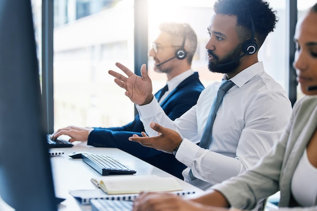 Call-Center-Kundenbetreuung und -Support mit einem männlichen Berater in einem Headset, der an einem Computer in seinem Büro arbeitet. Kontaktieren Sie uns CRM und Telemarketing mit einer männlichen Beratung bei einem Anruf an seinem Schreibtisch