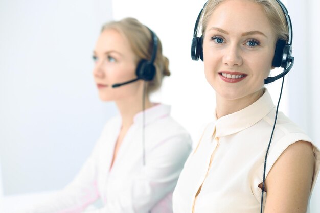 Call center luminoso y soleado. Grupo de mujeres rubias con auriculares en el trabajo. Concepto de oficina y negocio.