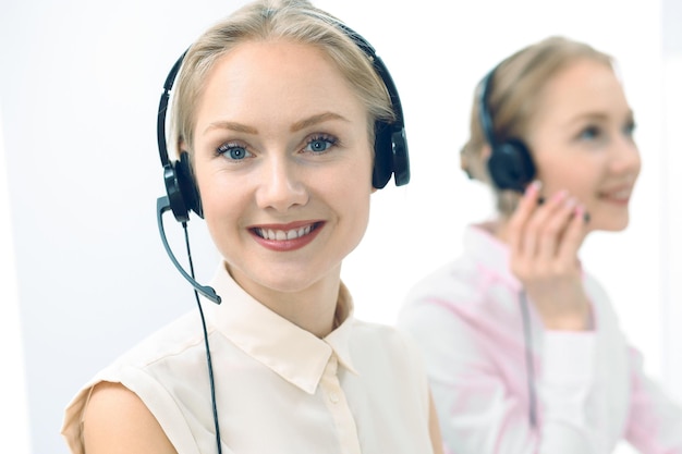 Call center luminoso y soleado. Grupo de mujeres rubias con auriculares en el trabajo. Concepto de oficina y negocio.