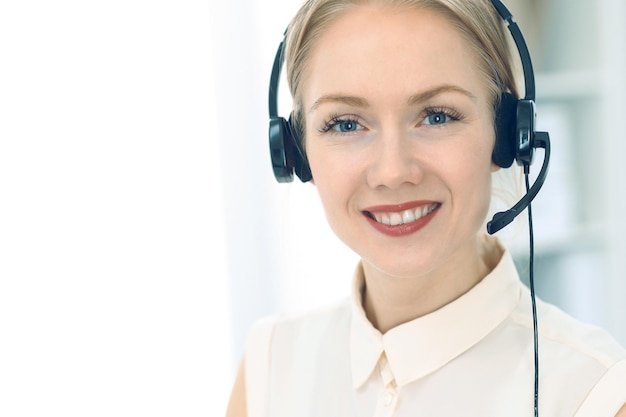 Call center luminoso y soleado. Grupo de mujeres rubias con auriculares en el trabajo. Concepto de oficina y negocio.