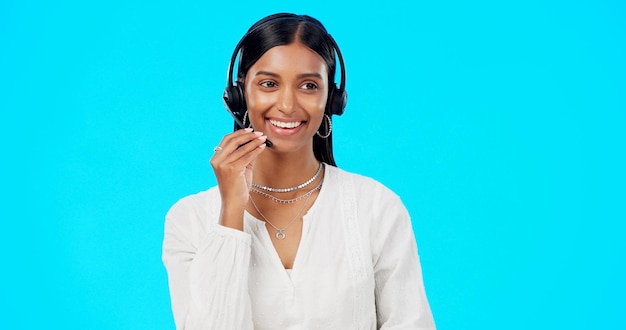 Foto call center mulher engraçada ou rindo no estúdio para comunicação em maquete de fundo azul atendimento ao cliente amigável crm ou menina indiana no fone de ouvido ajudando a falar ou explicando para suporte técnico