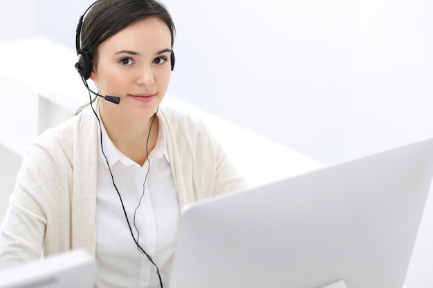 Call center Recepcionista de mulher bonita sentada no fone de ouvido no escritório de atendimento ao cliente