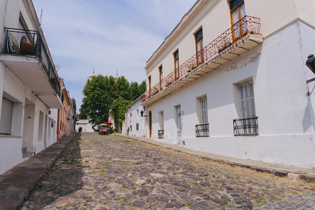 Calle adoquinada en la ciudad de Colonia del Sacramento en Uruguay con un coche de alquiler al fondo febrero de 2023