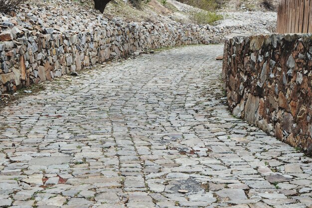 Foto calle de adoquines junto a un muro de piedra