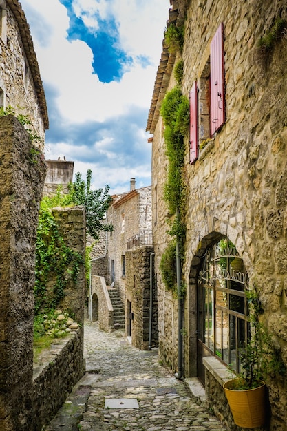 Calle angosta de adoquines y casa antigua con persianas en el pueblo medieval de Labeaume en Ardeche