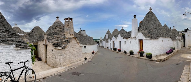 Calle bordeada por casas famosas los trulli con techo cónico en el sur de Italia en Puglia en el pueblo de Alberobello