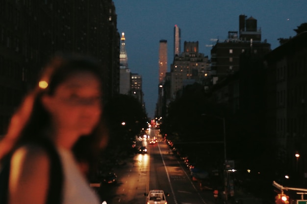 Foto calle de la ciudad iluminada con la mujer en primer plano por la noche