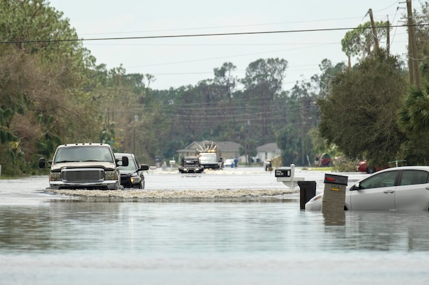 Foto una calle de la ciudad inundada con coches en movimiento sumergidos bajo el agua en una zona residencial de florida después de que el huracán ian tocara tierra.