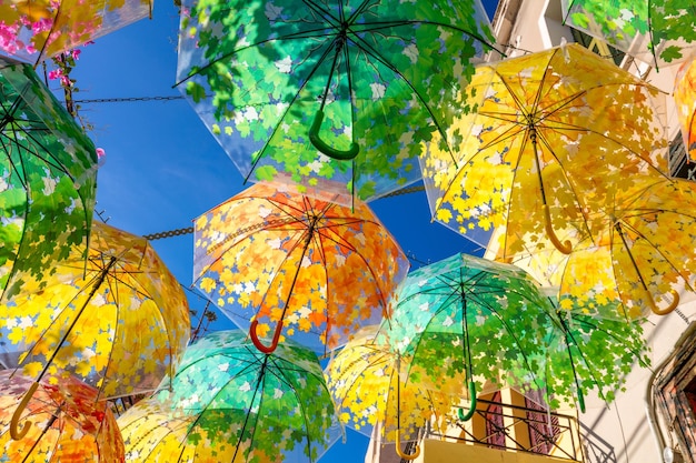 Calle decorada con sombrillas de diferentes colores en el casco antiguo en un día soleado de verano en la isla de Aegina Grecia Europa