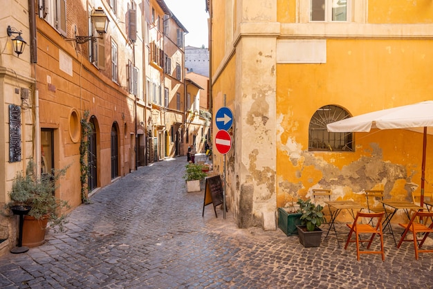 Calle estrecha con cafetería y pequeñas tiendas en roma.