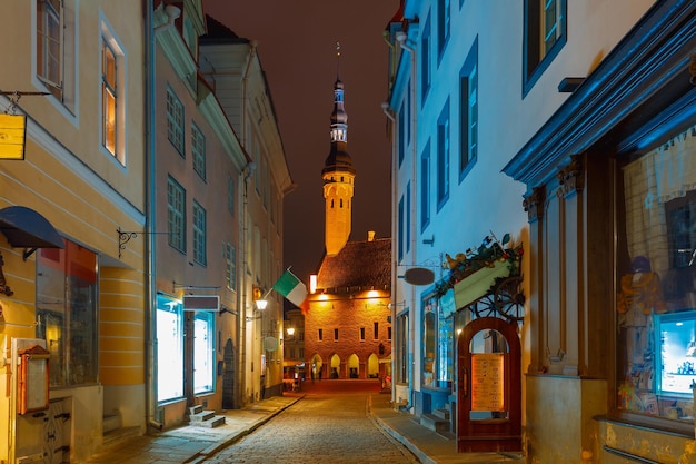 Calle estrecha iluminada del casco antiguo por la noche Ayuntamiento en el fondo Tallinn Estonia