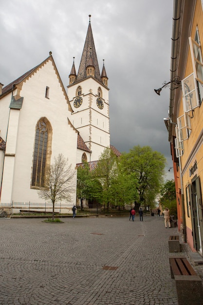 Una calle frente a una iglesia con una torre de reloj en el lado izquierdo.