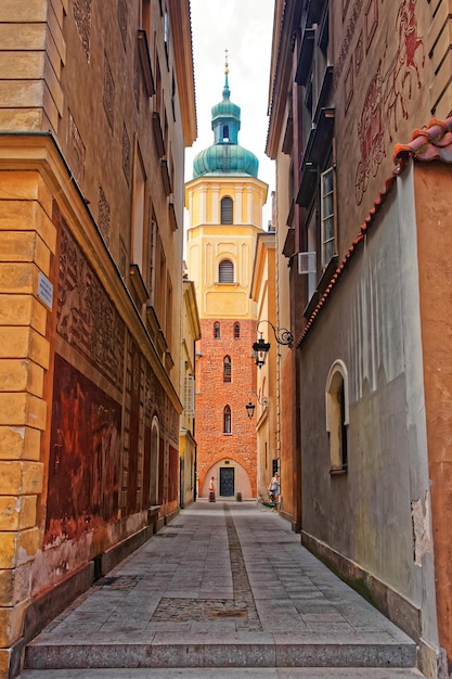 Calle y gente en el casco antiguo con vistas a la iglesia Spire of St Martin en Varsovia, Polonia