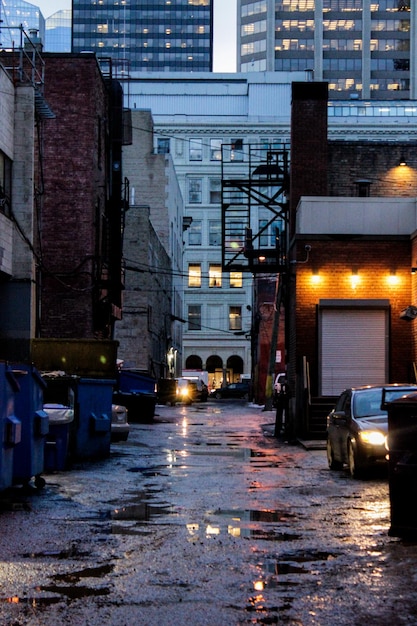 Foto calle húmeda en medio de los edificios por la noche