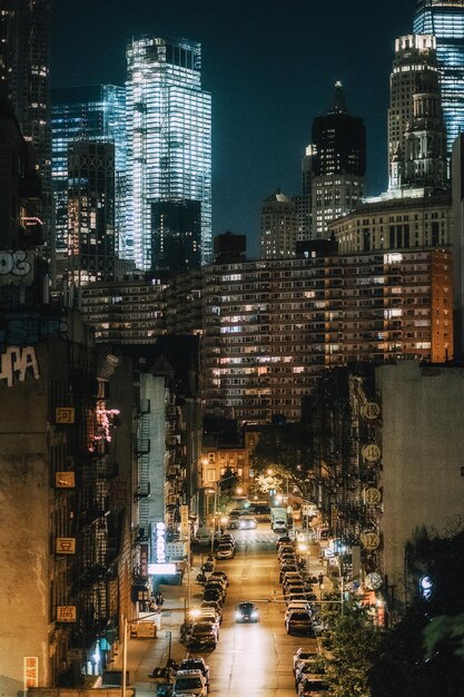 Foto calle iluminada en medio de edificios en la ciudad por la noche
