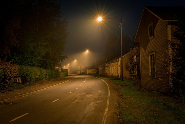 Una calle con una luz y una casa en el lado derecho.