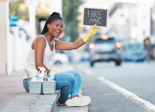 Calle de mujer y cartel para buscar trabajo o contratar trabajo de servicio de limpieza u oportunidad en la ciudad Limpiadora de mujer negra o trabajadora independiente doméstica en la acera del metro con letrero de cesta o producto