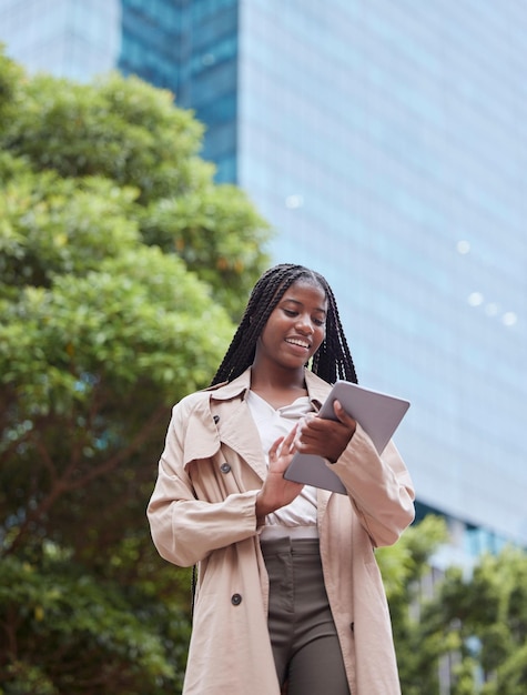 Calle de negocios de tabletas y mujer negra en la ciudad navegando por Internet o investigando Empleado de tecnología y ángulo bajo de mujer feliz con pantalla táctil para leer redes de correo electrónico o redes sociales al aire libre