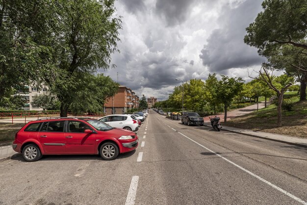 Foto una calle con un parque urbano a un lado y una batería de autos.