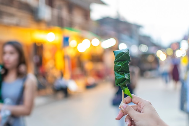 Calle peatonal de Chiang Khan: sosteniendo a Miang Kham Un plato local hecho con hierbas cubiertas con salsa y envuelto en hojas de betel.