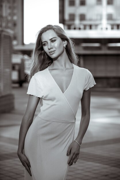 Calle retrato de una hermosa mujer joven con cuerpo delgado y cabello largo y rubio. Tonificación en blanco y negro