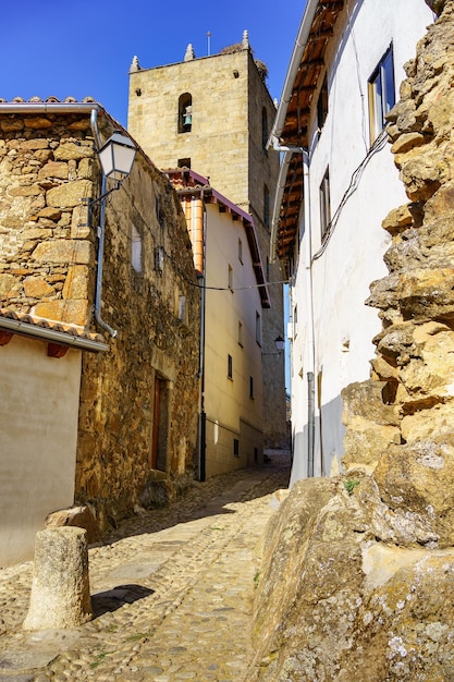 Callejón estrecho con sus pintorescas casas antiguas y la torre de la iglesia del pueblo en el fondo Barco de Ávila España