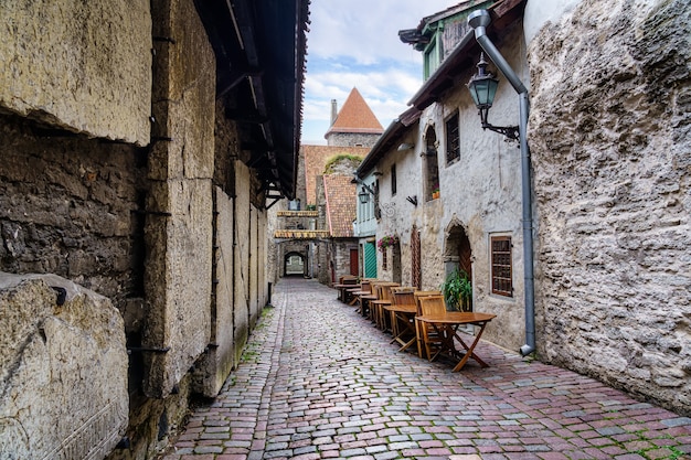 Callejón medieval con casas de piedra y torre del castillo en Tallin, Estonia.