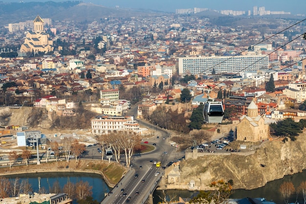 Calles de la ciudad vieja de Tbilisi río Kura Iglesia de la Santísima Trinidad y teleférico en primer plano Georgia