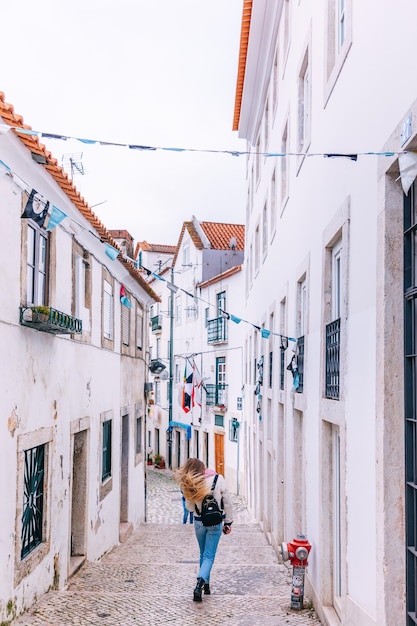 calles estrechas de Lisboa la capital de Portugal chica con ropa elegante camina por las calles de la ciudad vista de atrás