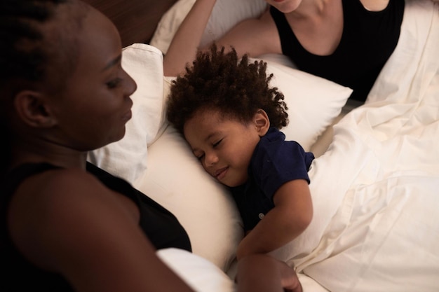 Calma menino feliz dormindo na cama de seus pais dormindo e conceito de rotina de hora de dormir