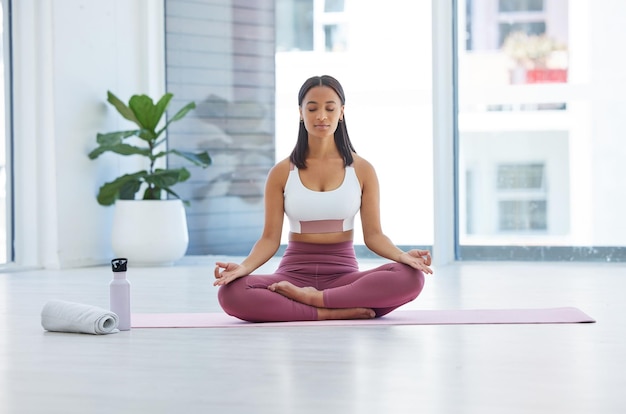 Calma la mente por completo. Foto de una joven deportista meditando mientras hace ejercicio en un estudio de yoga.