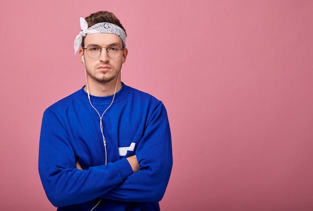 Calma rapaz de bandana branca e blusa azul, ouvindo música com fones de ouvido