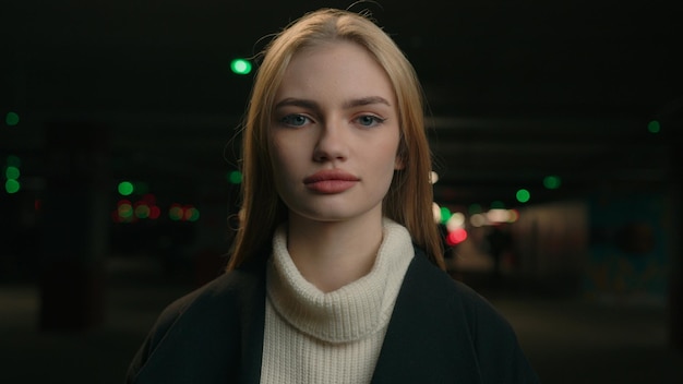 Calma señora mujer caucásica independiente en el fondo de estacionamiento oscuro chica rubia enfocada mirando