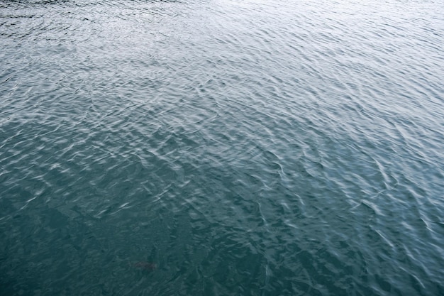 Foto calma de la superficie del agua del mar con fondo de color azul profundo del océano de ondulación pequeña