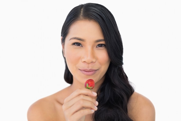 Calmo modelo de cabelo castanho atraente comendo morango