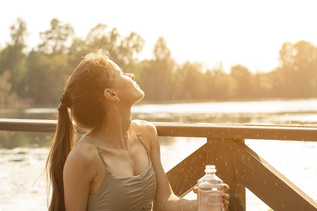 calor de verano adolescente bebe agua sentado junto al estanque